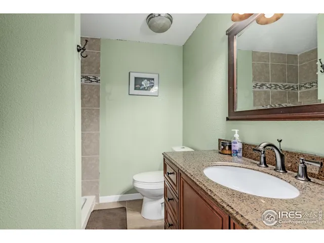a bathroom with a granite countertop sink a mirror and a toilet