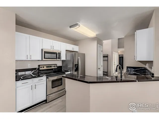 a kitchen with stainless steel appliances kitchen island granite countertop a stove a sink and white cabinets