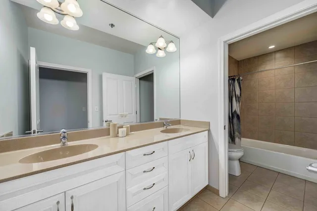 a bathroom with a granite countertop sink a toilet a mirror and shower