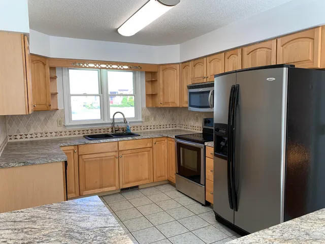 a kitchen with stainless steel appliances granite countertop a refrigerator sink and cabinets