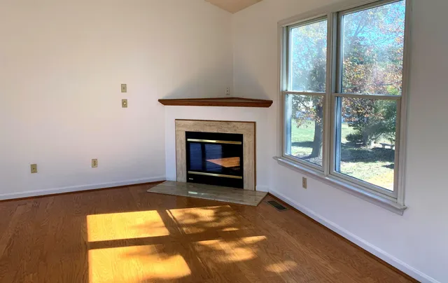 a view of an empty room with a fireplace and a window