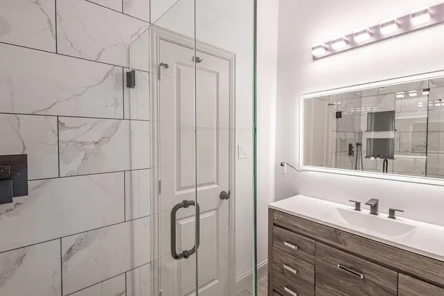 a bathroom with a granite countertop sink a mirror and shower