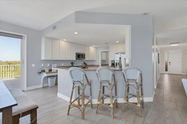 a kitchen with stainless steel appliances granite countertop a dining table chairs stove a refrigerator and cabinets