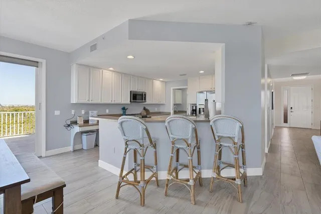 a kitchen with stainless steel appliances granite countertop a dining table chairs stove a refrigerator and cabinets