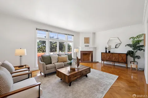 a living room with furniture a rug potted plant and a large window
