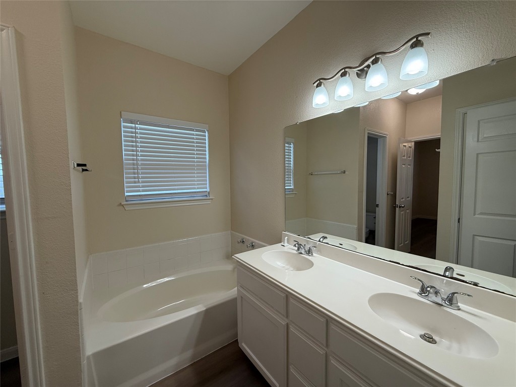 303 Kates Way Hutto, TX 78634 - Photo 8 of 15 a bathroom with a tub a sink double vanity and a mirror