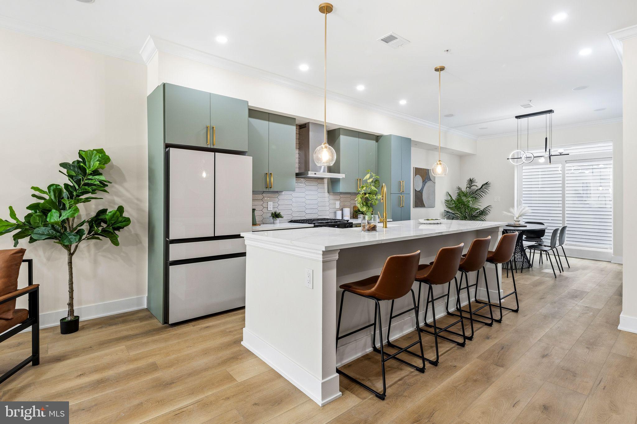 1731 Reed Street Philadelphia, PA 19146 - Photo 8 of 42 a kitchen with stainless steel appliances kitchen island granite countertop a refrigerator a stove a sink and a dining table with wooden floor