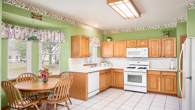 a kitchen with a stove a sink dishwasher a dining table and chairs with wooden floor