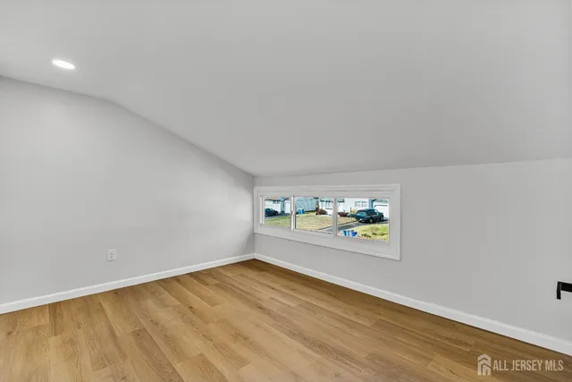 a view of a hallway with wooden floor and a bathroom