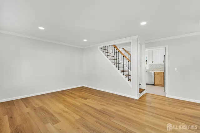 a view of an empty room with wooden floor and stairs
