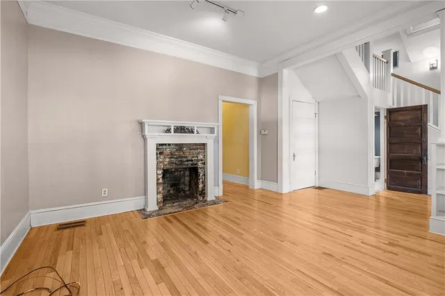 a view of empty room with wooden floor and fireplace