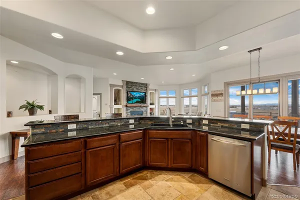 a kitchen with stainless steel appliances kitchen island granite countertop a dining table chairs refrigerator sink and cabinets