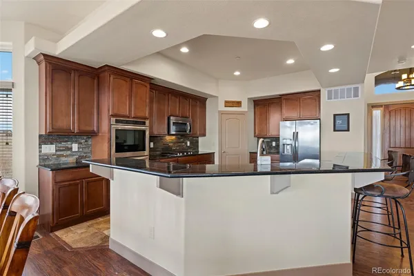 a kitchen with stainless steel appliances a sink a stove a refrigerator cabinets and a dining table