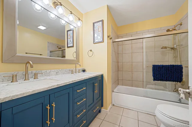 a bathroom with a granite countertop sink a toilet a mirror a bathtub and shower