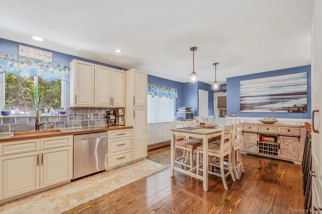 a kitchen with stainless steel appliances a dining table chairs stove and white cabinets