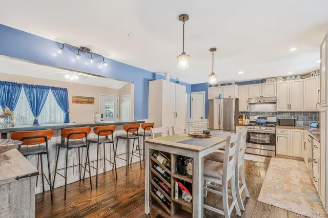 a kitchen with stainless steel appliances kitchen island granite countertop a table chairs in it and wooden floors