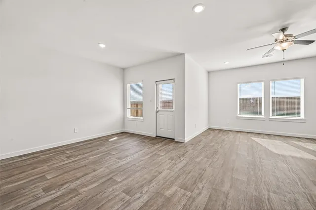 a view of an empty room with a window and wooden floor