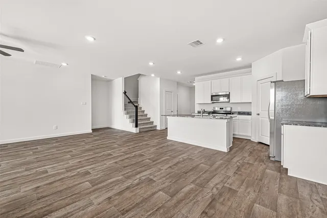 a view of kitchen with kitchen island a sink wooden floor and stainless steel appliances