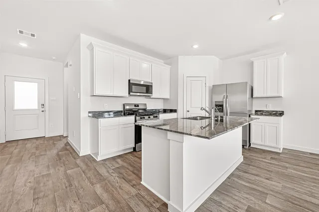 a kitchen with white cabinets appliances and sink