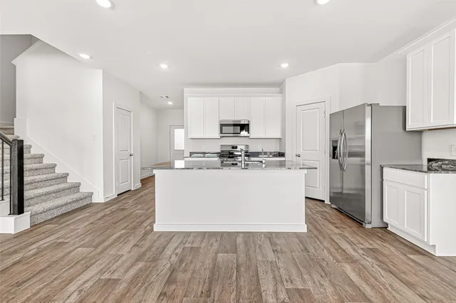 a kitchen with wooden floors white cabinets and stainless steel appliances