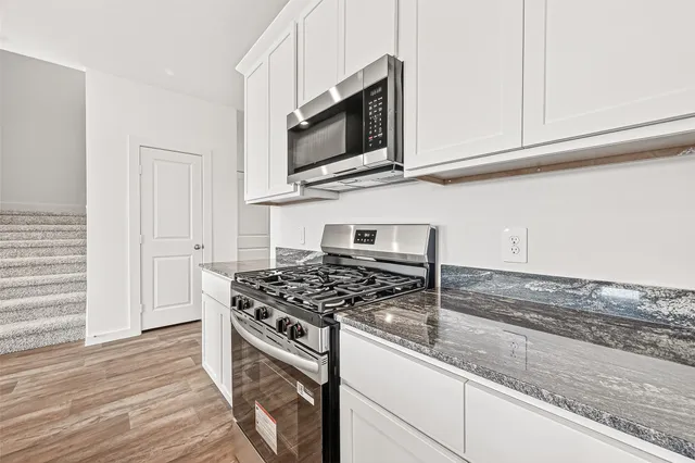 a kitchen with stainless steel appliances granite countertop a stove a microwave and a sink