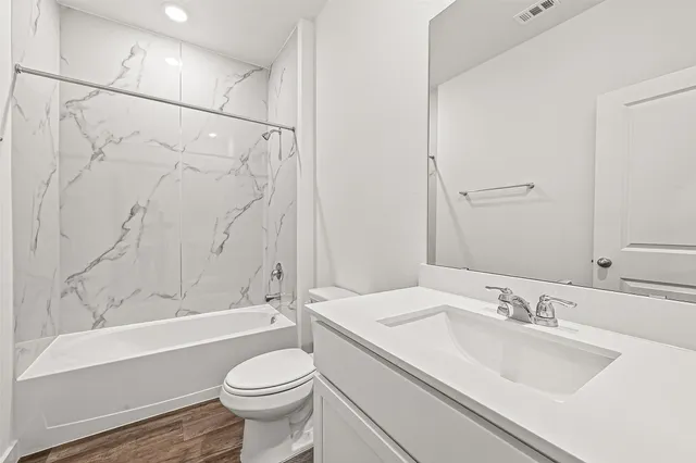 a bathroom with a granite countertop sink toilet and shower