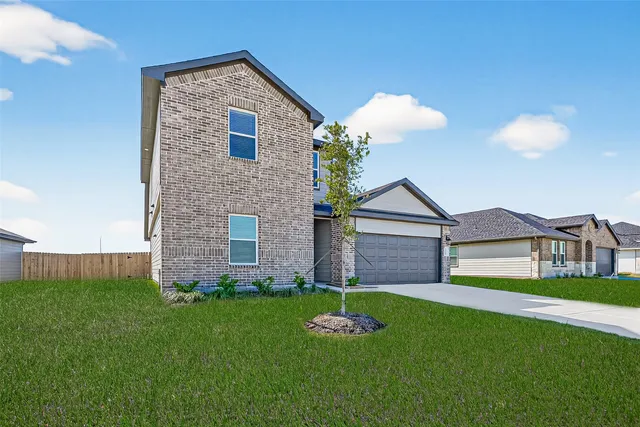 a brick house with a yard and a large tree
