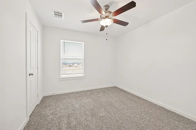 an empty room with a window and a fan