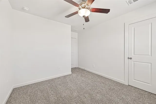an empty room with a chandelier fan and a ceiling fan