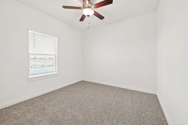 an empty room with a window and a fan