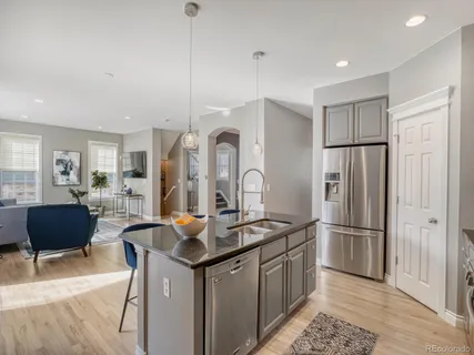 a kitchen with stainless steel appliances granite countertop a refrigerator a stove and a sink with wooden floor