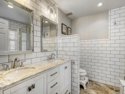a bathroom with a granite countertop sink a toilet and mirror