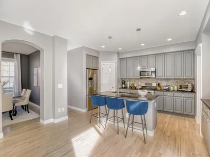 a kitchen with stainless steel appliances kitchen island granite countertop wooden floors and white cabinets