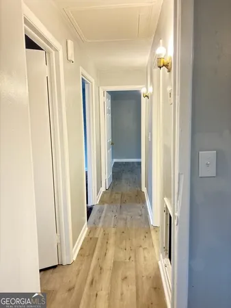 a view of a hallway with wooden floor and a bathroom