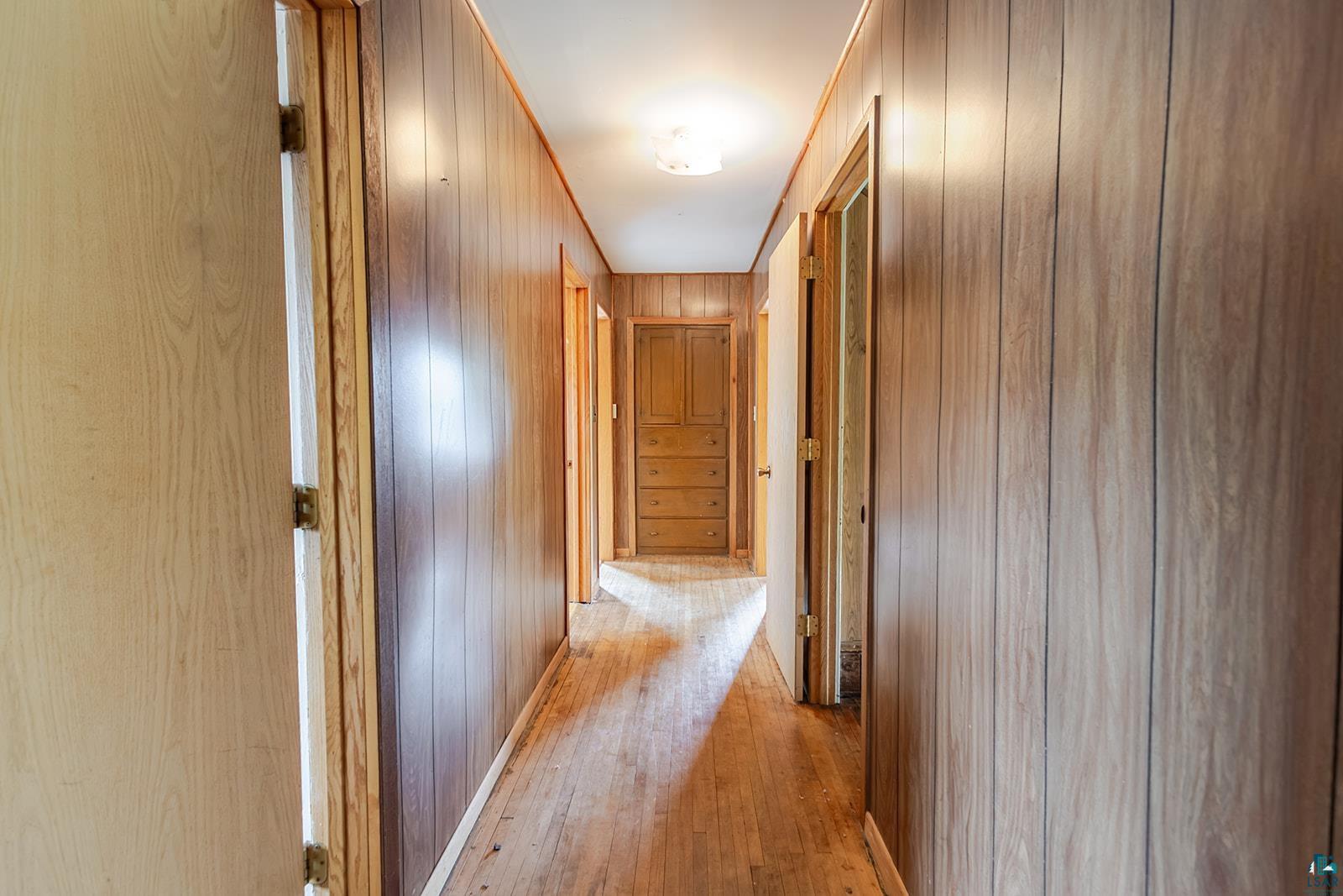 438 9th Street Cloquet, MN 55720 - Photo 17 of 27 Hallway featuring wood-finish paneling, wood-finish flooring, and multiple doorways