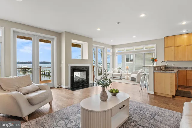 a living room with couches and kitchen view with wooden floor