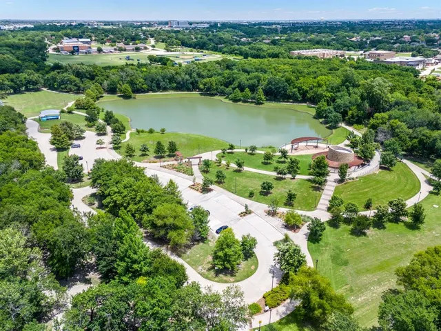 an aerial view of green landscape with trees houses and lake view