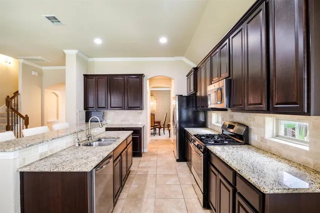 a kitchen with stainless steel appliances granite countertop a sink stove and refrigerator