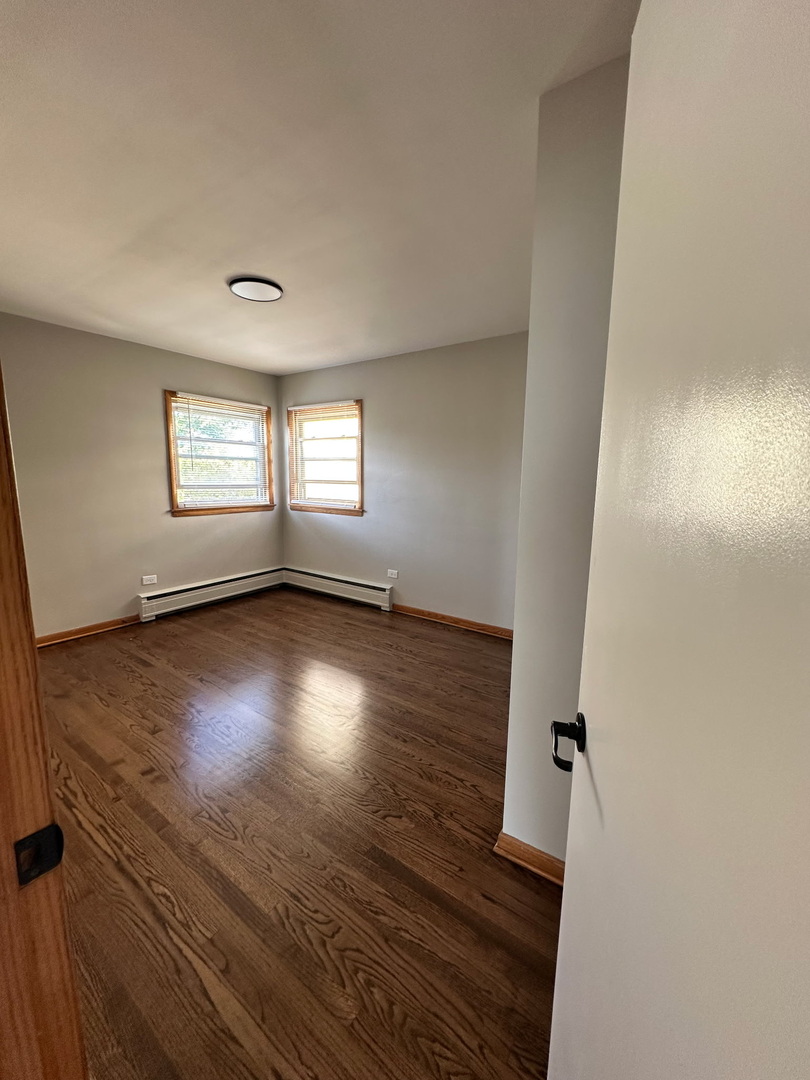 7538 Waukegan Road, Unit 1W Niles, IL 60714 - Photo 3 of 9 an empty room with wooden floor and windows