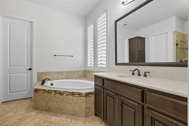 a spacious bathroom with a tub sink and mirror