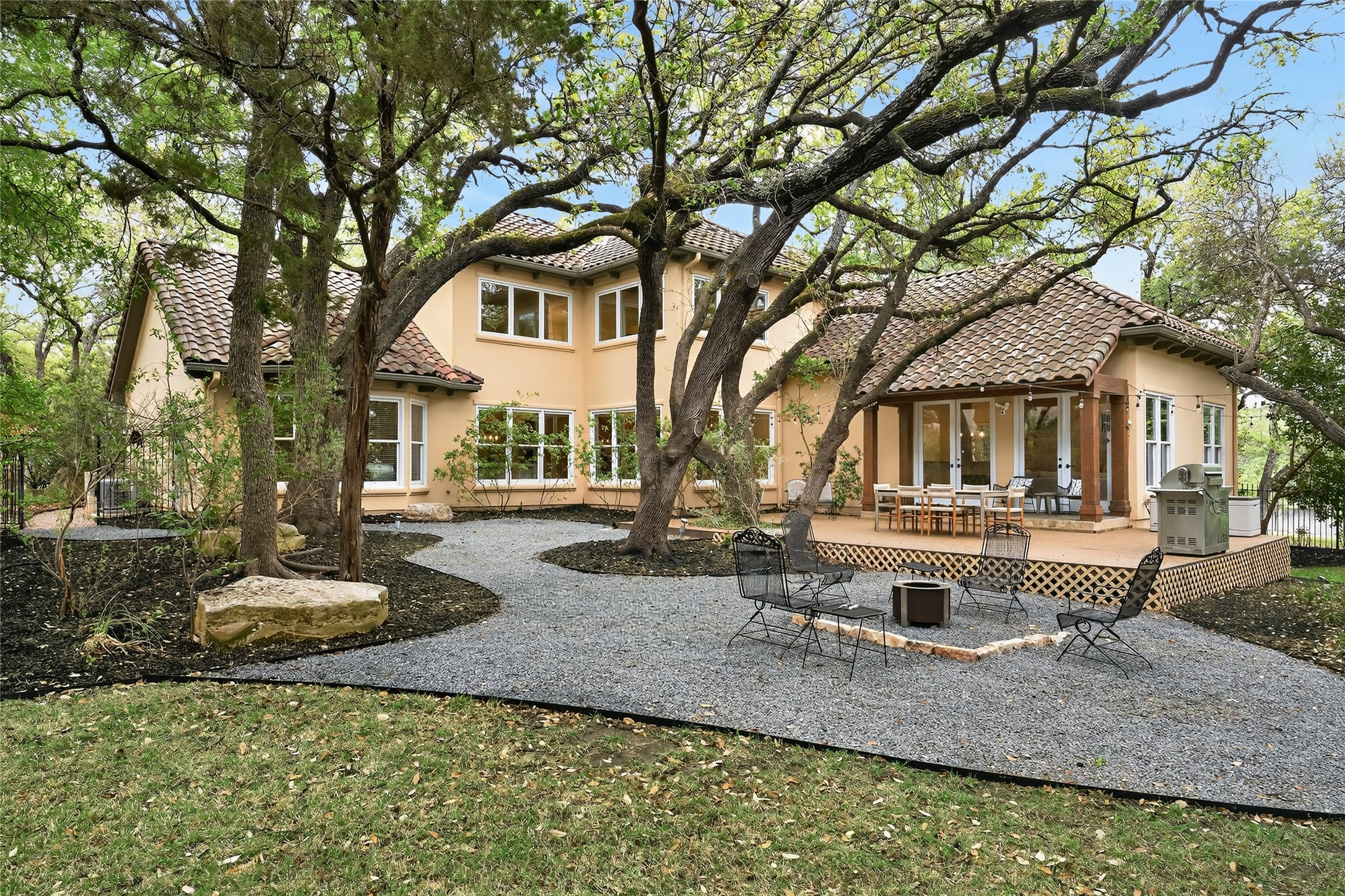 4110 Bunny Run, Unit 3 Austin, TX 78746 - Photo 1 of 35 The property features a spacious backyard with a large deck, a gravel patio area with a fire pit, and mature trees providing natural shade