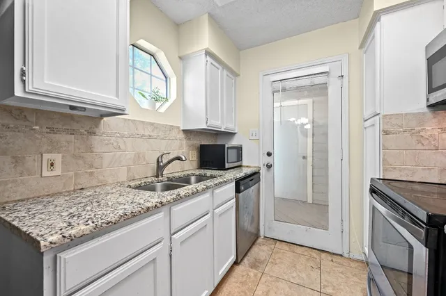 a kitchen with stainless steel appliances granite countertop a refrigerator a table and chairs