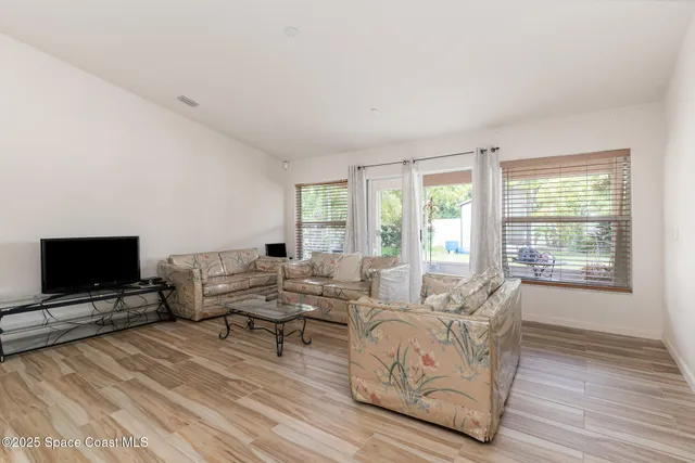 a living room with furniture a flat screen tv and a floor to ceiling window