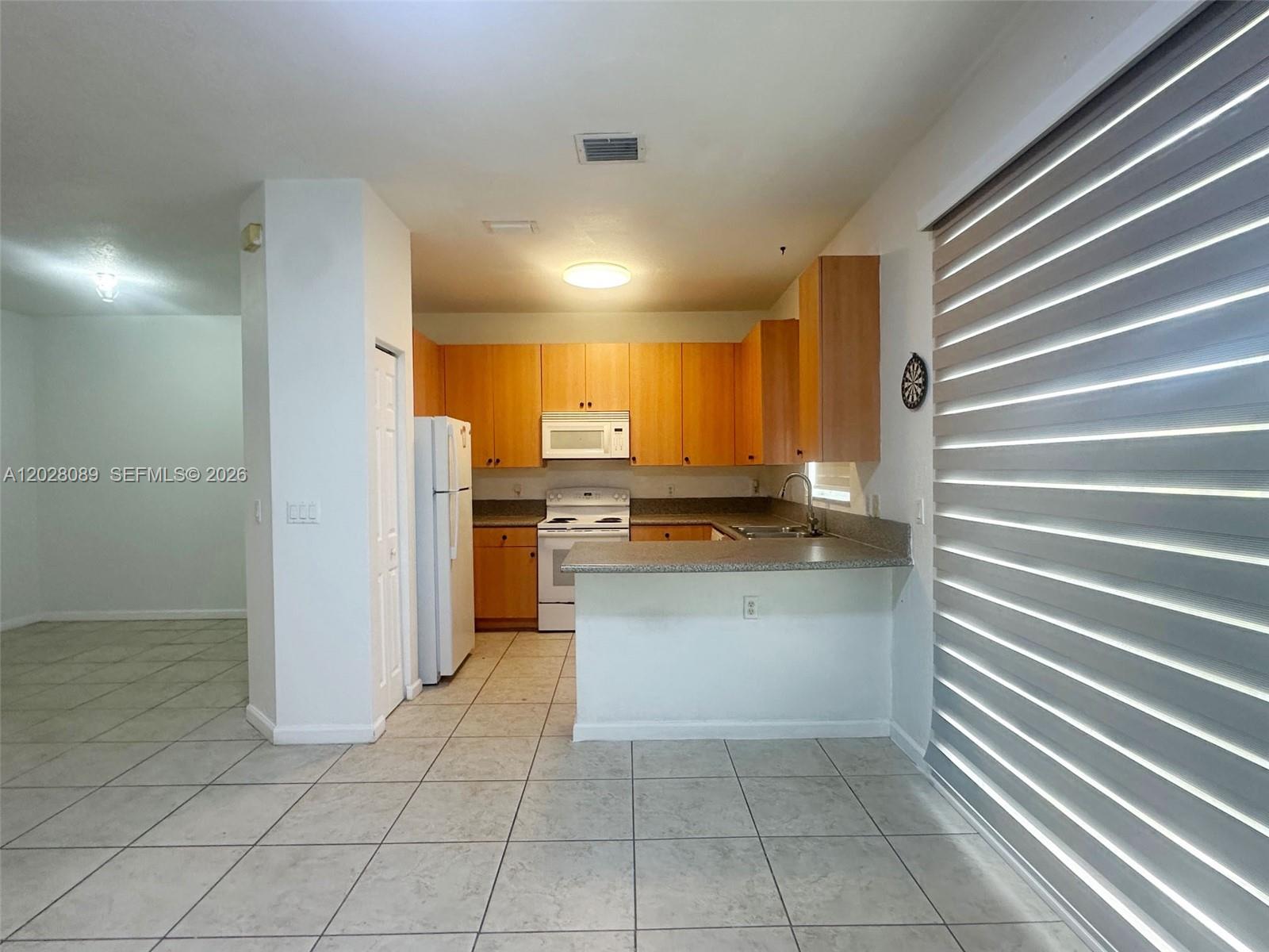 662 Northeast 21st Terrace Homestead, FL 33033 - Photo 9 of 34 a kitchen with a refrigerator and white cabinets