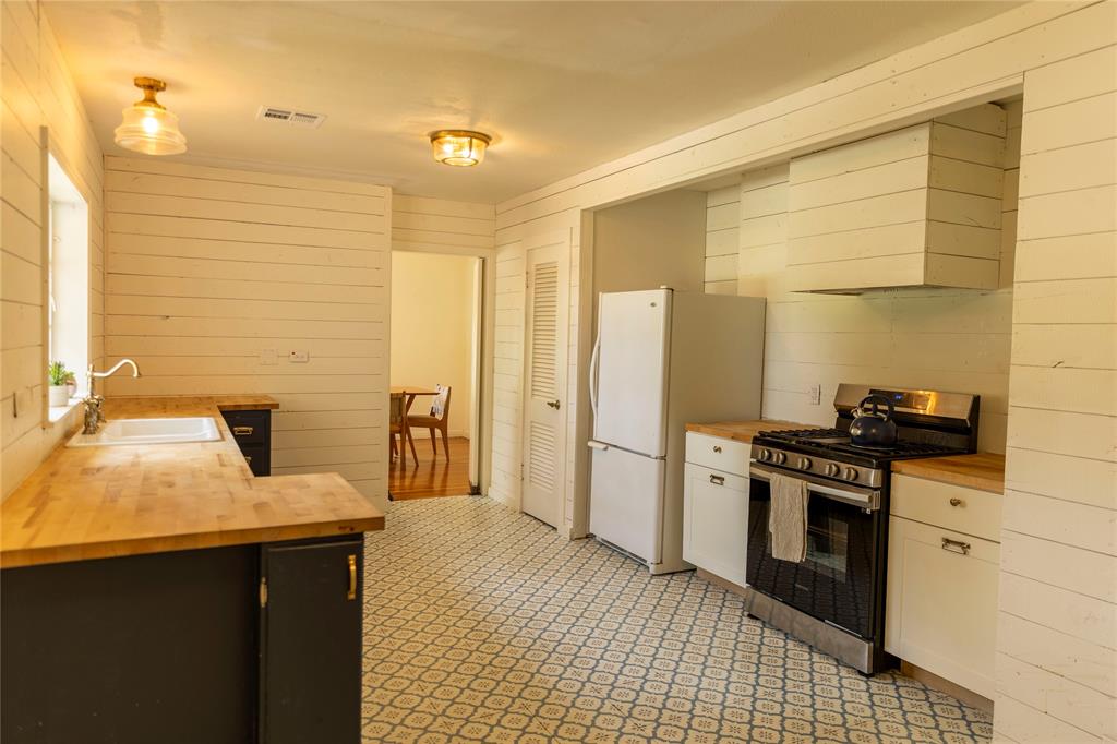 3228 Colcord Avenue Waco, TX 76707 - Photo 7 of 29 Kitchen featuring wood-finish countertops, geometric-patterned floor tile, white shiplap walls, and a built-in range with an integrated ventilation hood
