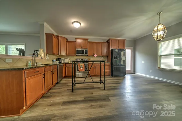 a kitchen with stainless steel appliances granite countertop a stove top oven a sink dishwasher and a refrigerator with wooden floor