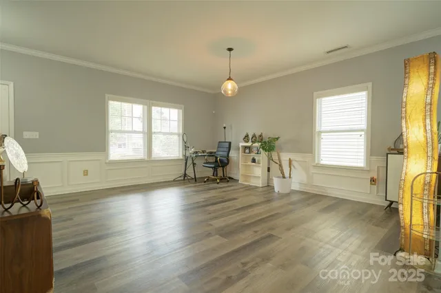 a view of an empty room with a window and wooden floor
