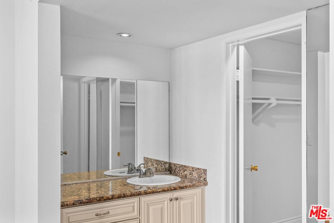 10535 Wilshire Boulevard, Unit 801 Los Angeles, CA 90024 - Photo 27 of 53 a bathroom with a granite countertop sink and a mirror
