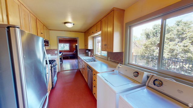 315 Abbey Road Moab, UT 84532 - Photo 18 of 46 Kitchen with stainless steel appliances, light countertops, washer and dryer, light wood finish cabinets, and dark flooring