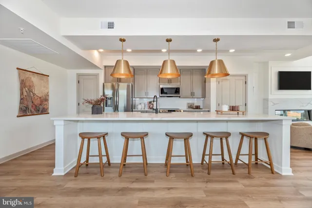 a view of kitchen with stainless steel appliances wooden floor and dining table